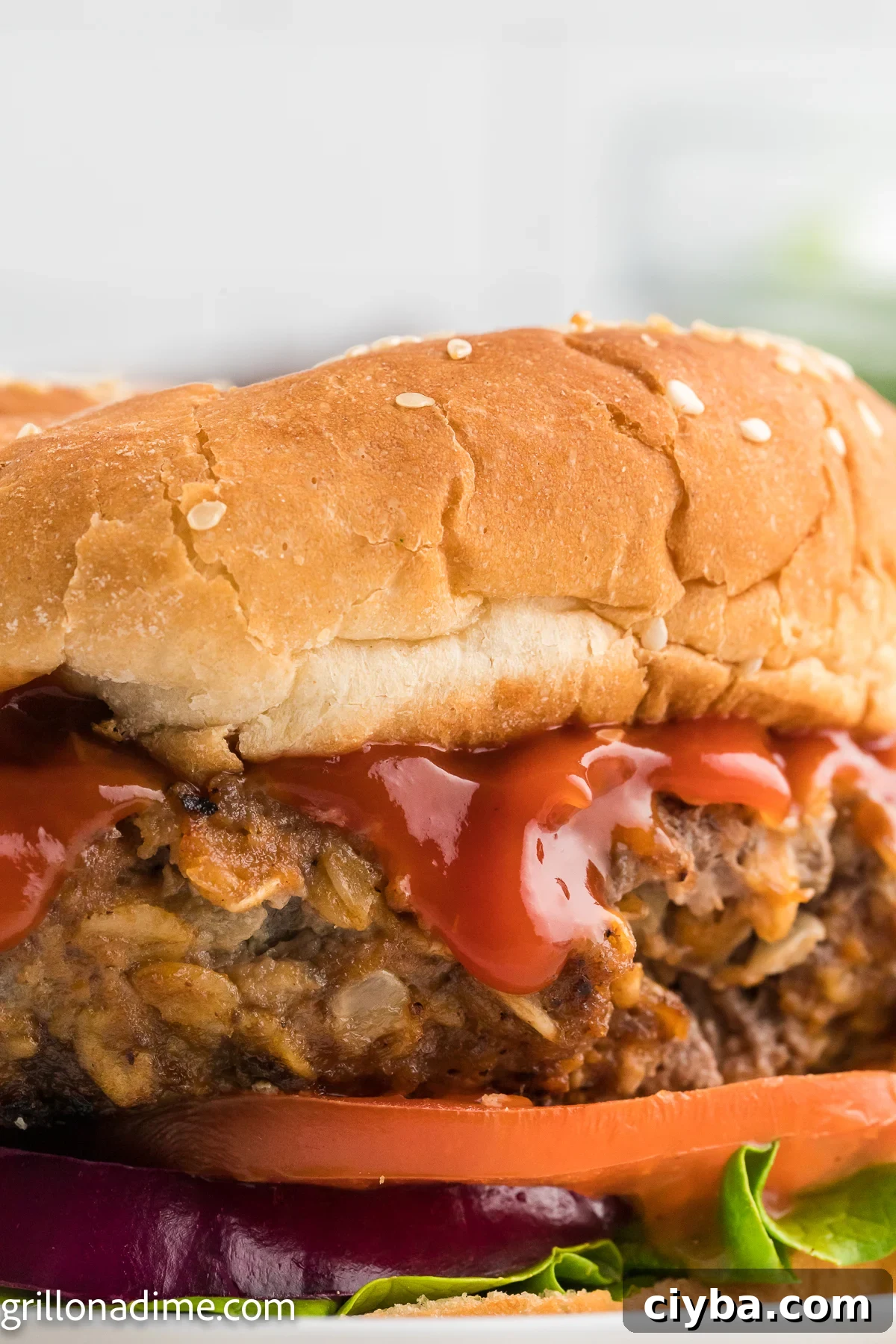 Meatloaf Burger on a plate layered with ketchup, slice tomatoes, red onion and lettuce