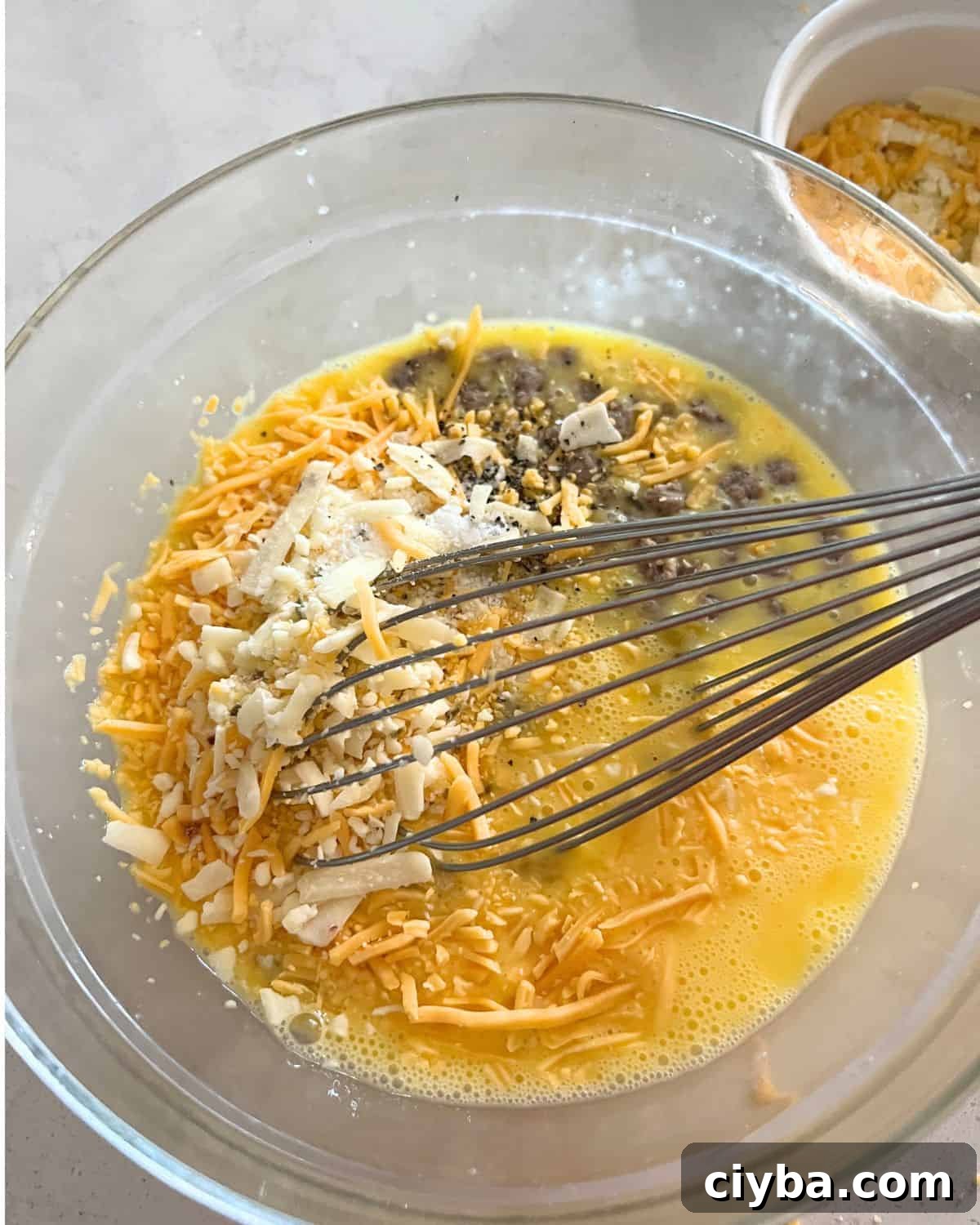 Ingredients for egg and sausage muffins in a bowl. 