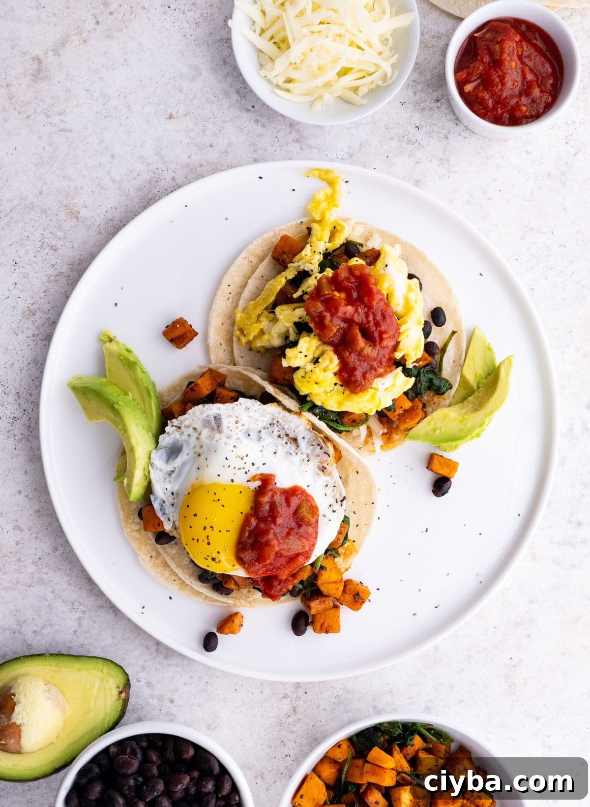 Sweet Potato and Black Bean Breakfast Tacos for Busy Mornings 3 Plate of sweet potato and black bean breakfast tacos with eggs and avocado on top, ready to eat.