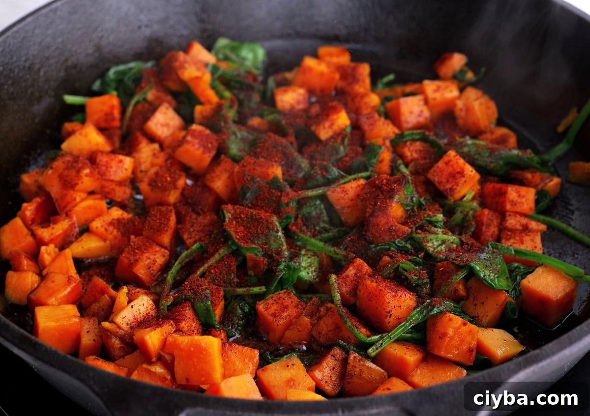 Sweet Potato and Black Bean Breakfast Tacos for Busy Mornings 5 Cast iron skillet with sweet potatoes, spinach, and chili powder cooking to make breakfast tacos