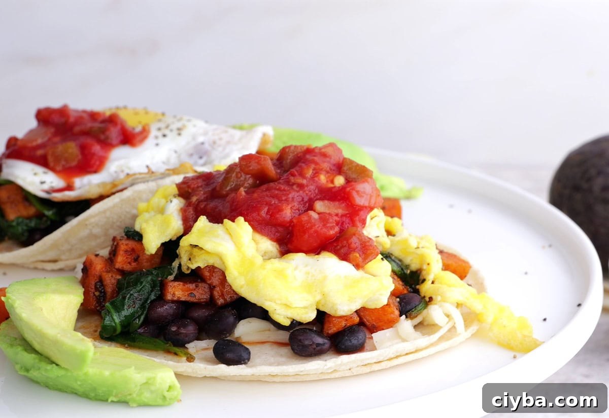 Sweet Potato and Black Bean Breakfast Tacos for Busy Mornings 8 Two breakfast tacos on a plate with scrambled eggs and salsa.