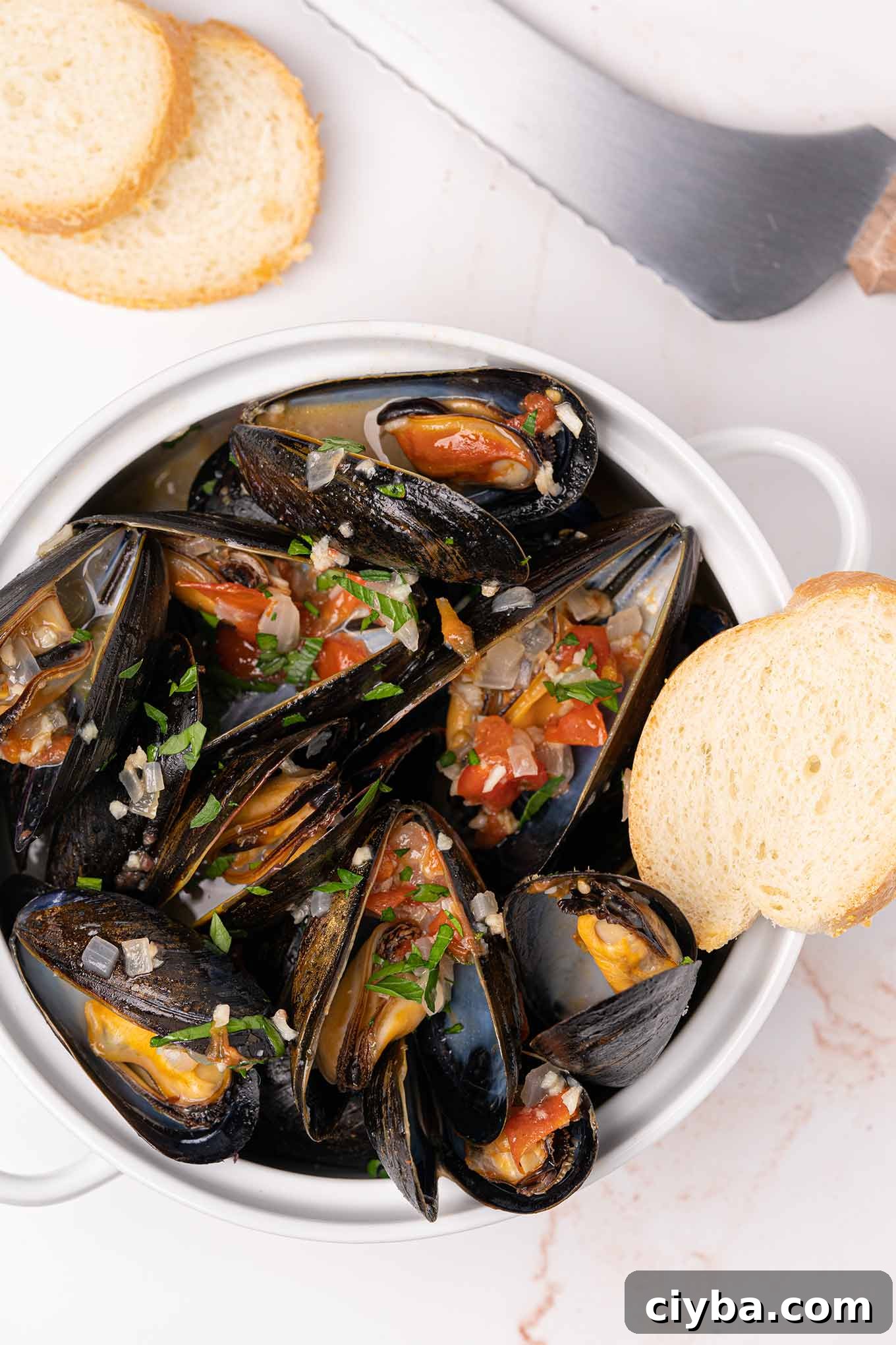 Italian-Style Steamed Mussels with Garlic, White Wine, and Herbs 2 Crock filled with steamed mussels topped with sautéed garlic, onion, diced tomatoes, and parsley,