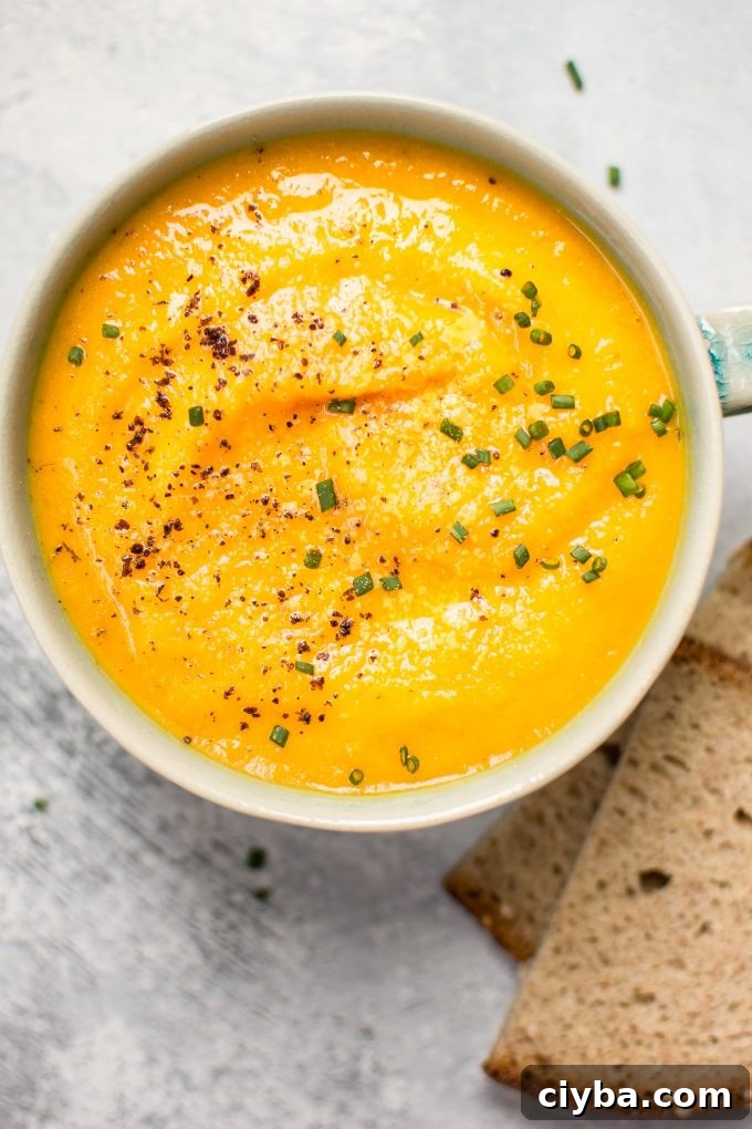 bowl of vegetarian acorn squash and carrot soup beside rye bread slices