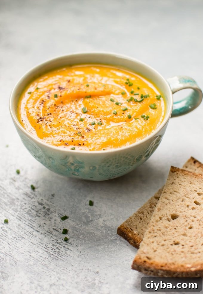 soup mug with vegetarian acorn squash and carrot soup beside rye bread slices