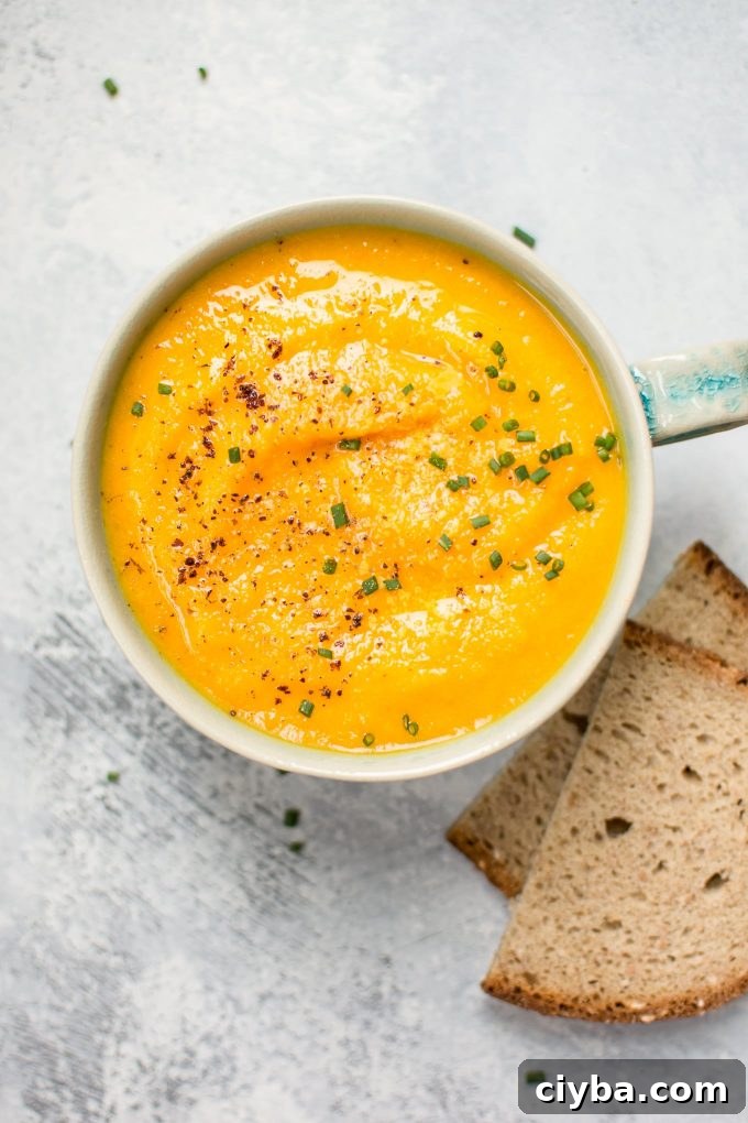 close-up of acorn squash carrot soup in a soup mug beside bread slices