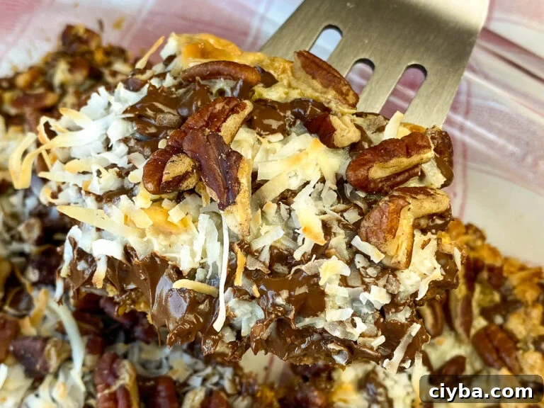 Silver cookie scoop lifting a gooey Eagle Magic Bars out of the serving dish.