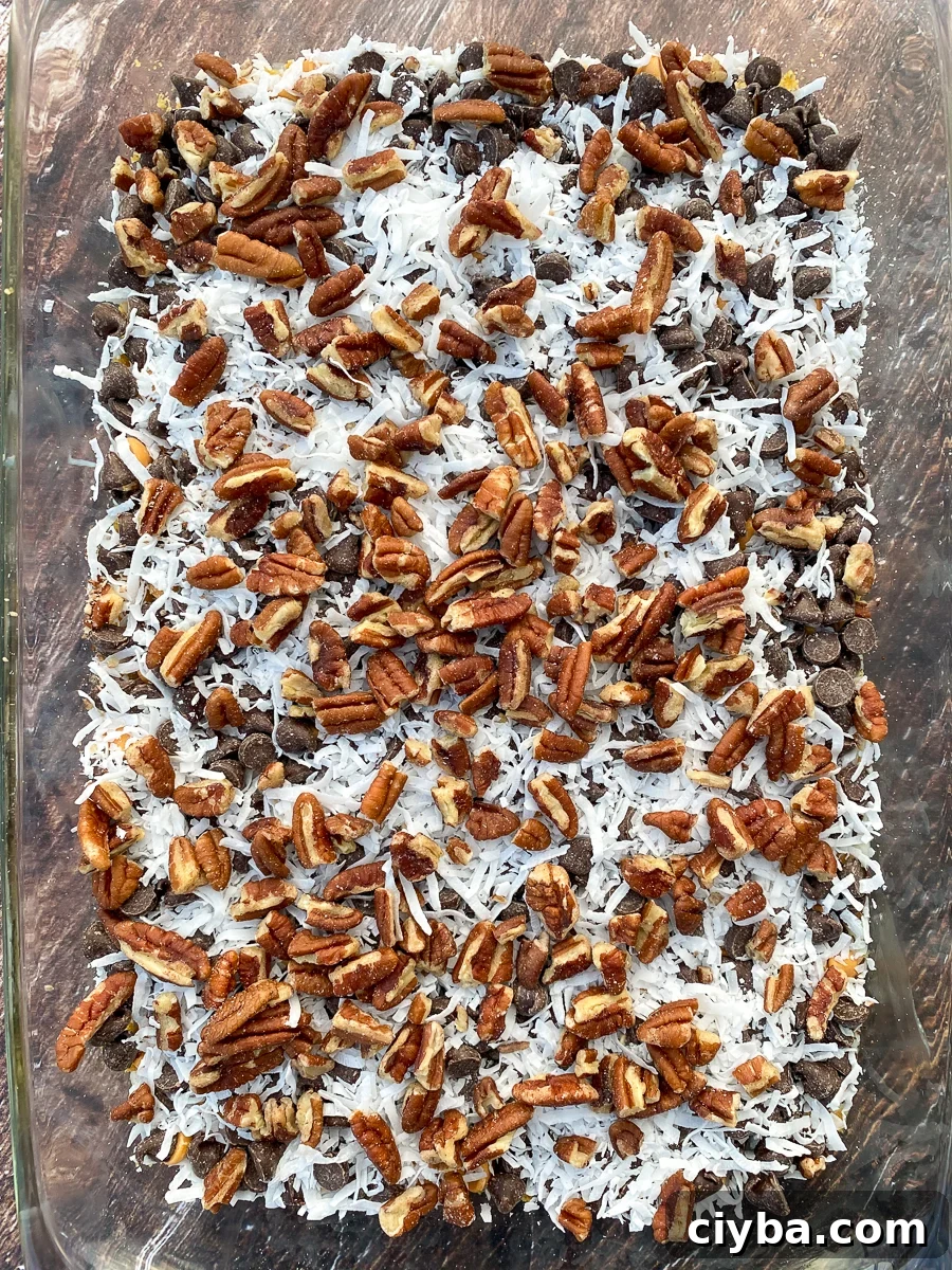 Chopped pecans scattered on top of magic cookie bars before baking
