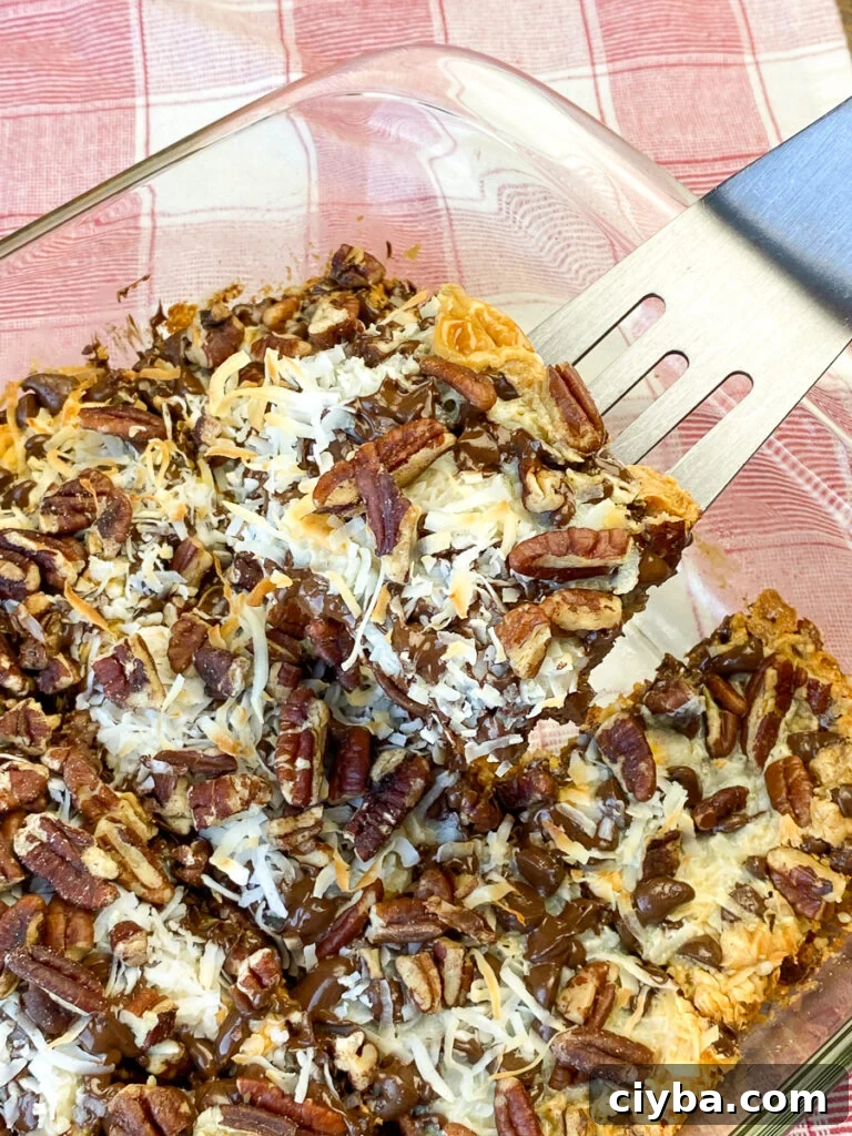 Browned coconut and pecans on top of chocolate, butterscotch, milk and graham cracker crust in seven layer magic cookie bars