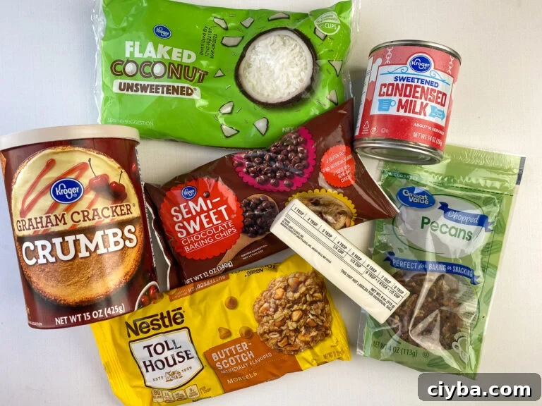 Seven ingredients to make magic cookie bars - flaked coconut, sweetened condensed milk, graham cracker crumbs, semi-sweet chocolate chips, butter, chopped pecan and butterscotch chips.