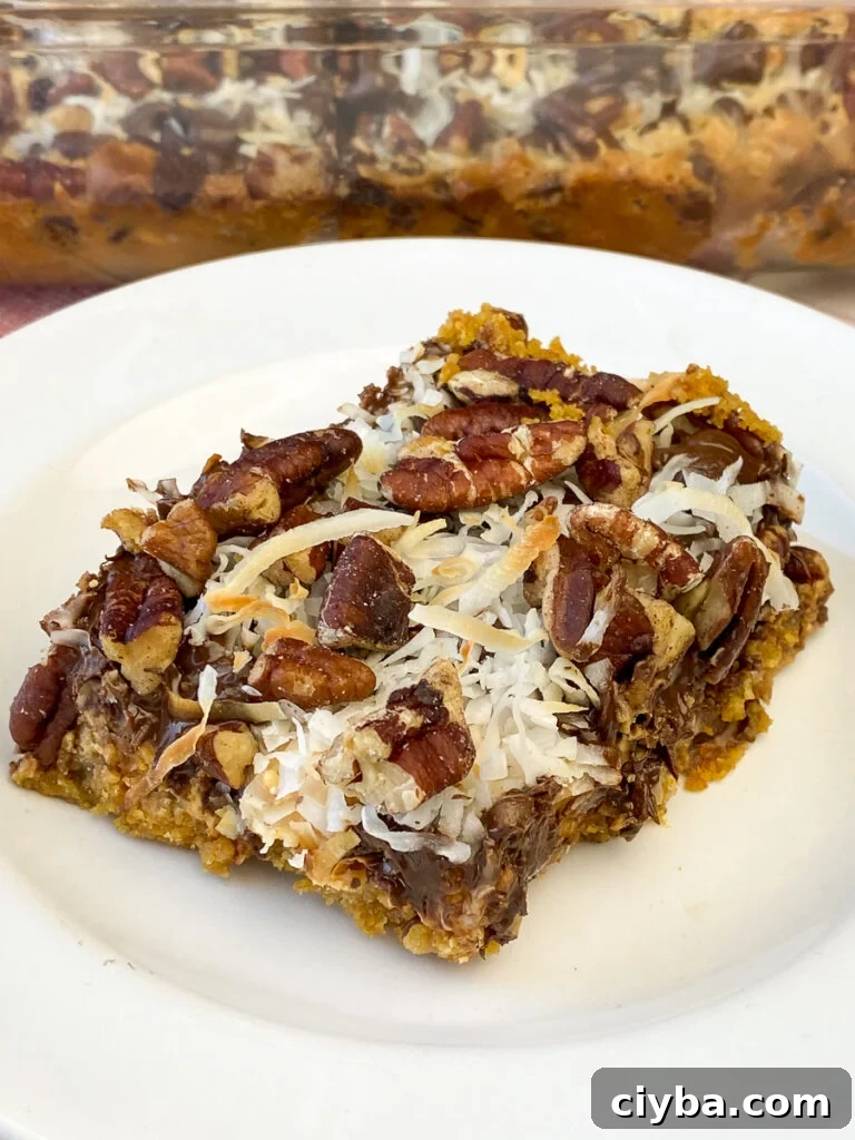 Loaded Eagle Brand Magic Cookie Bar on a white plate in front of the full dish