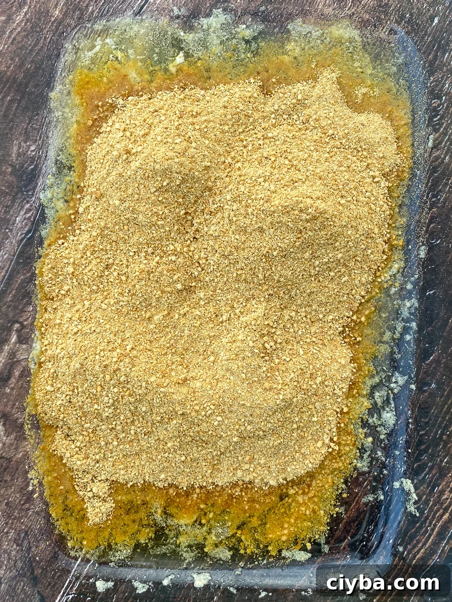 Graham cracker crumbs poured on top of melted butter in a 9x13 baking pan