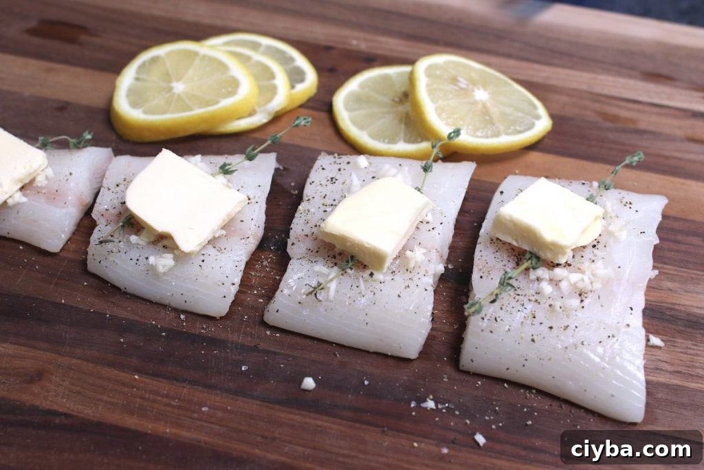 Raw halibut filets with seasoning and butter on top.