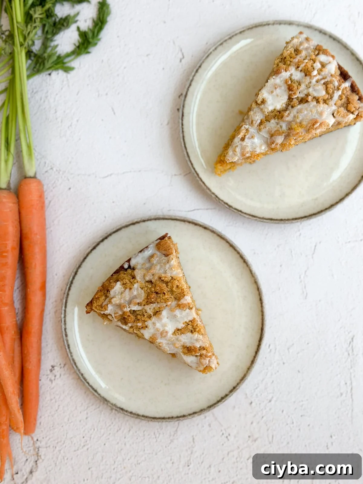 two slices of carrot cake coffee cake with some carrots on the side.