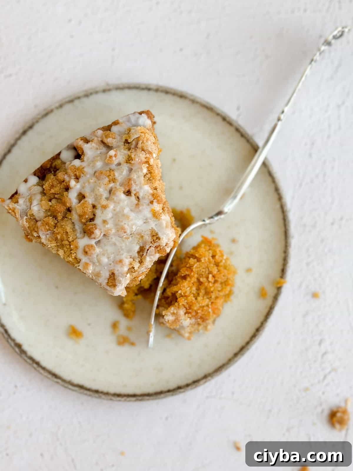 a single piece of carrot cake coffee cake on a plate with a fork cutting in.