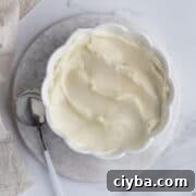 Diplomat cream in a white bowl with a spoon and towel in the background.