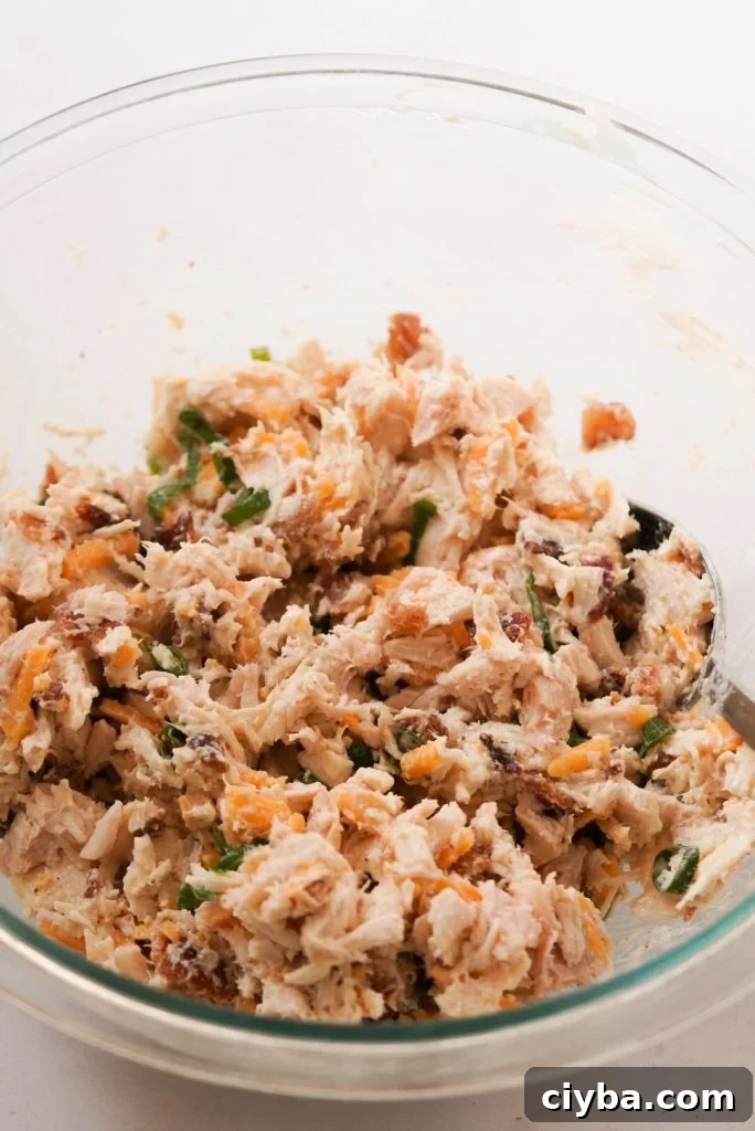 mixed chicken salad in a large bowl with bacon and cheddar cheese