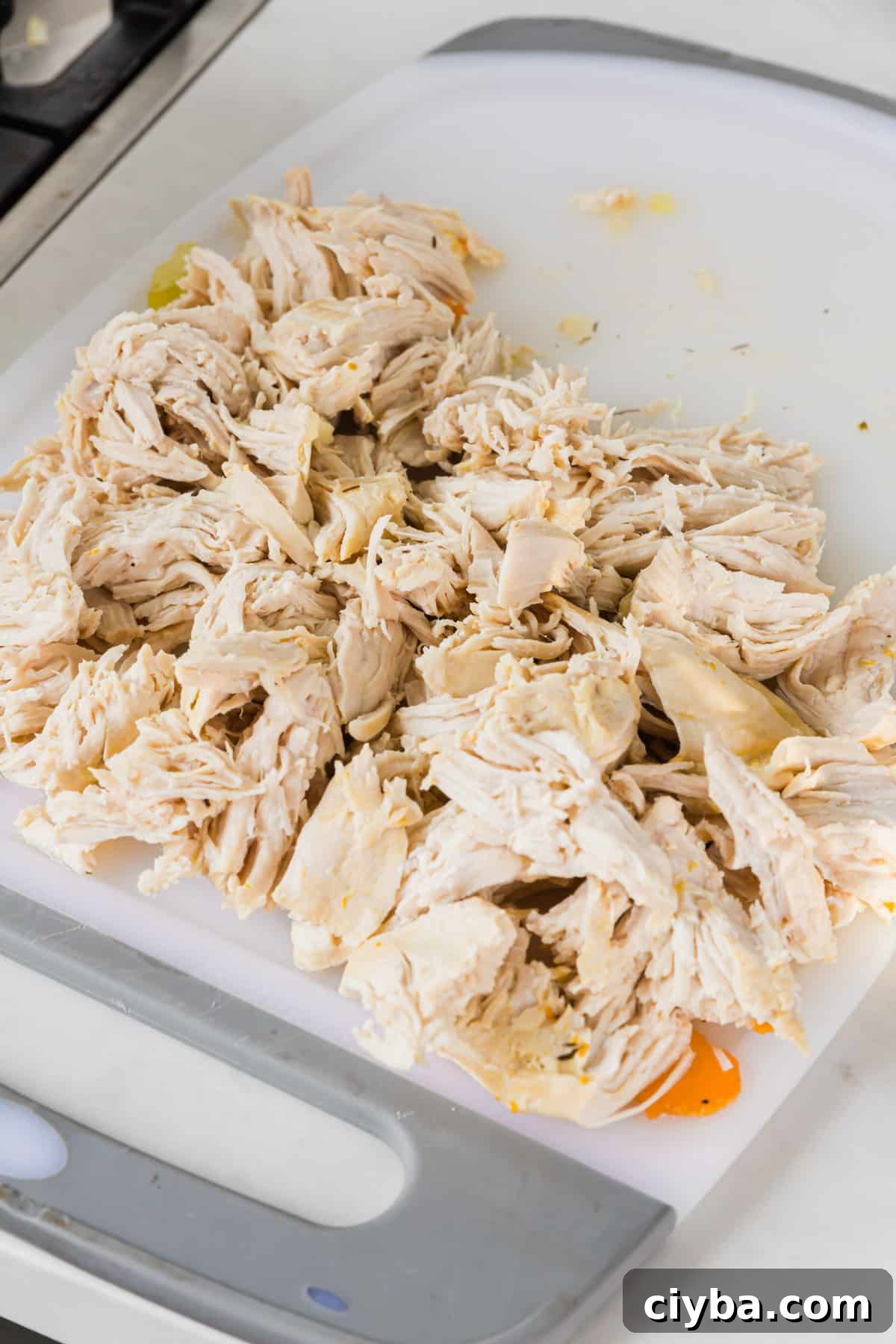 A cutting board with shredded chicken breast on it.