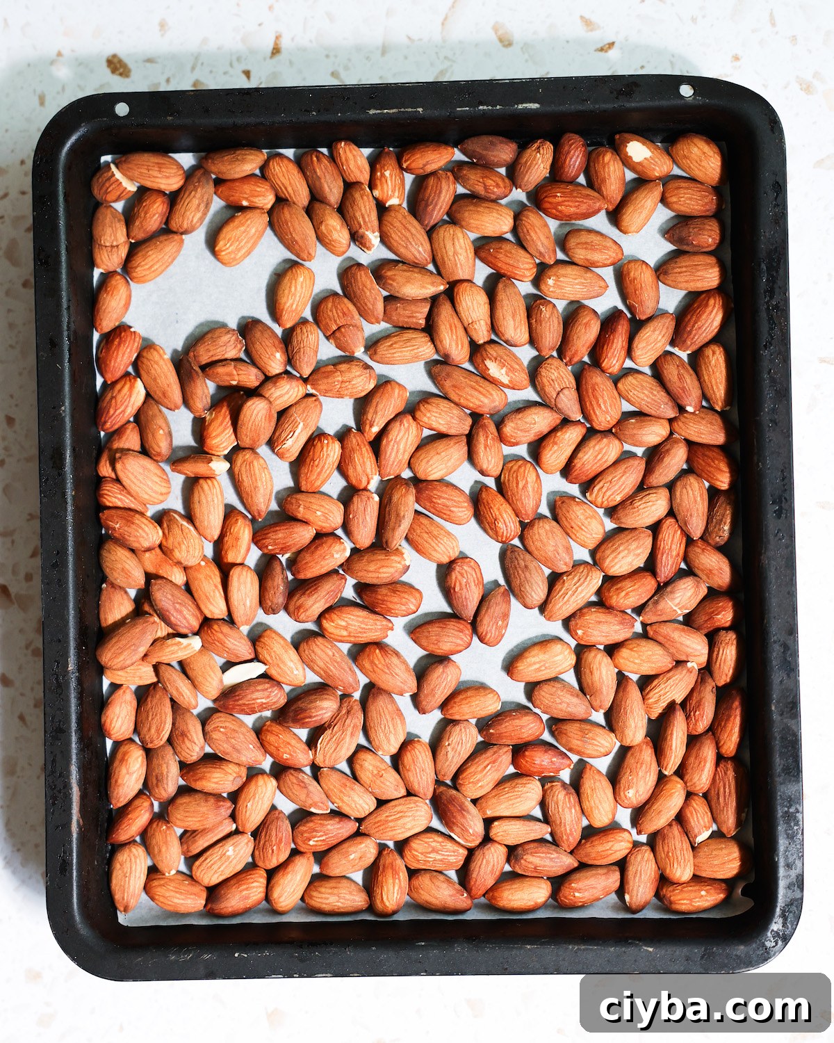 An overhead shot of a pan of tamari almonds before roasting.