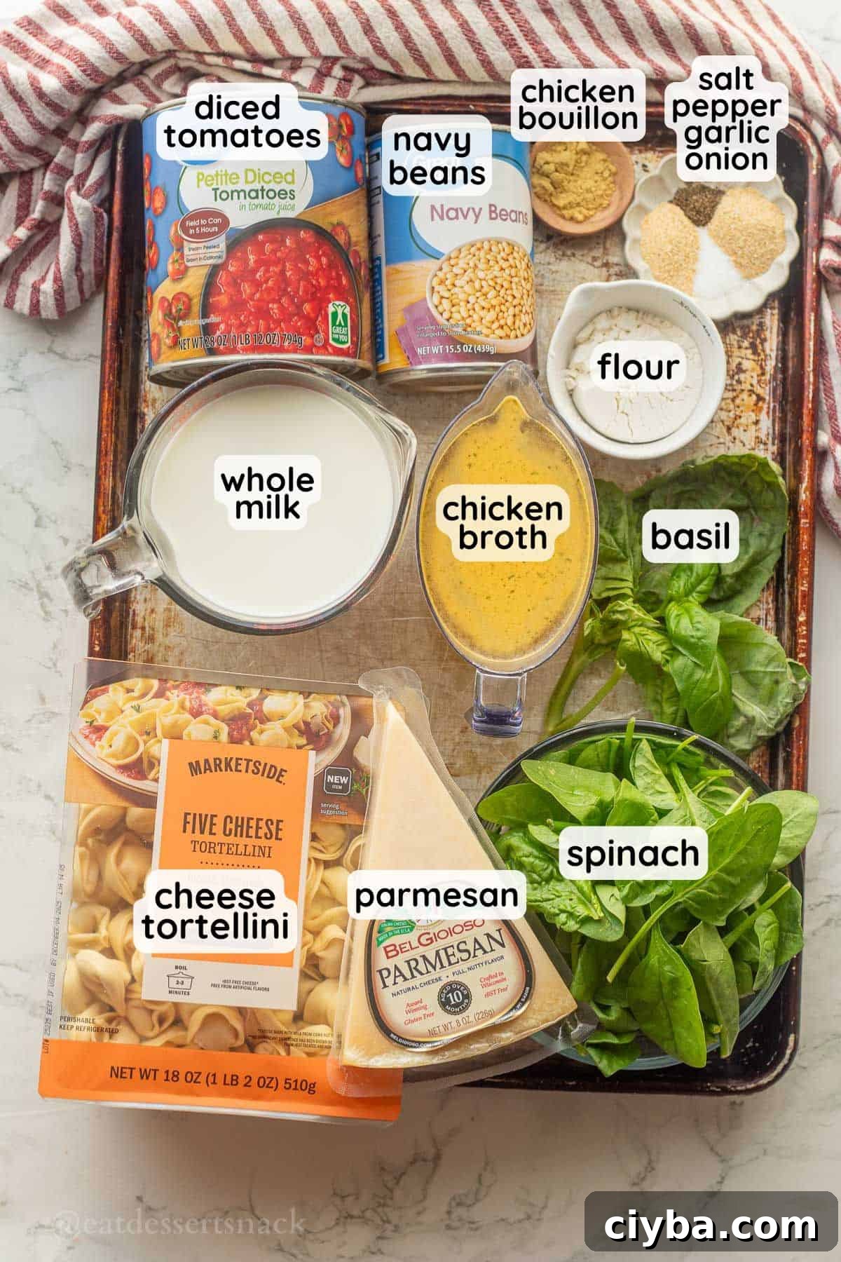 Labeled ingredient for tomato white bean tortellini soup in glass bowls on metal baking sheet.