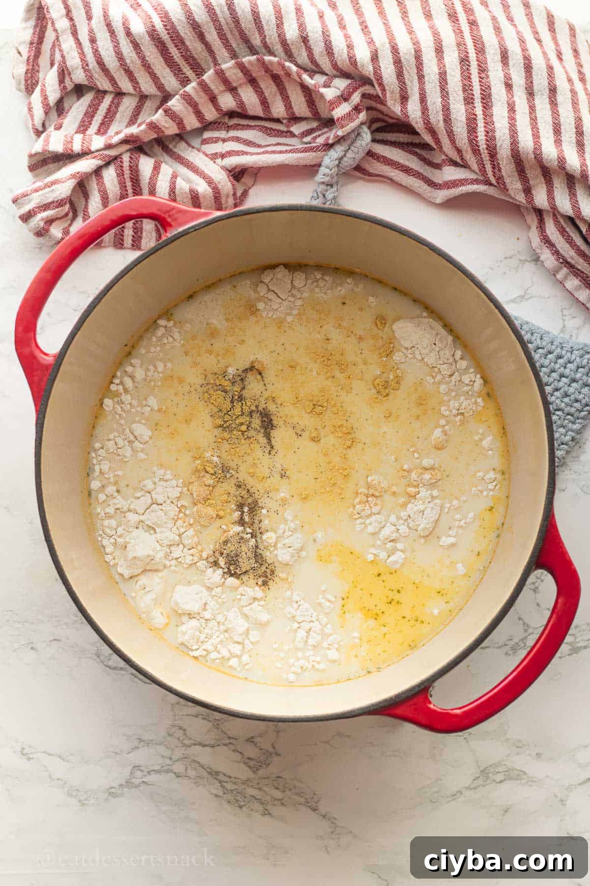 Flour and seasoning in soup broth in pot.