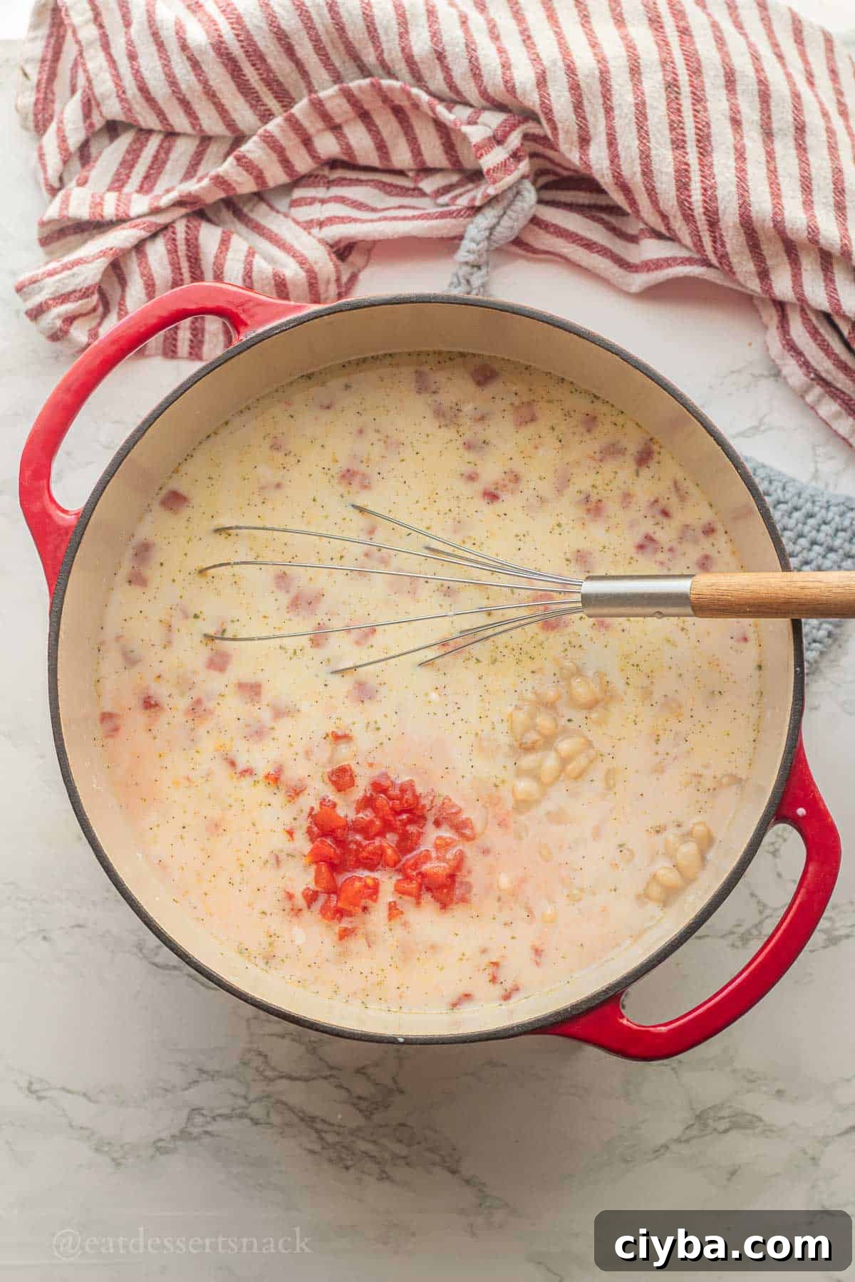 Tomatoes in soup pot with wooden spoon.