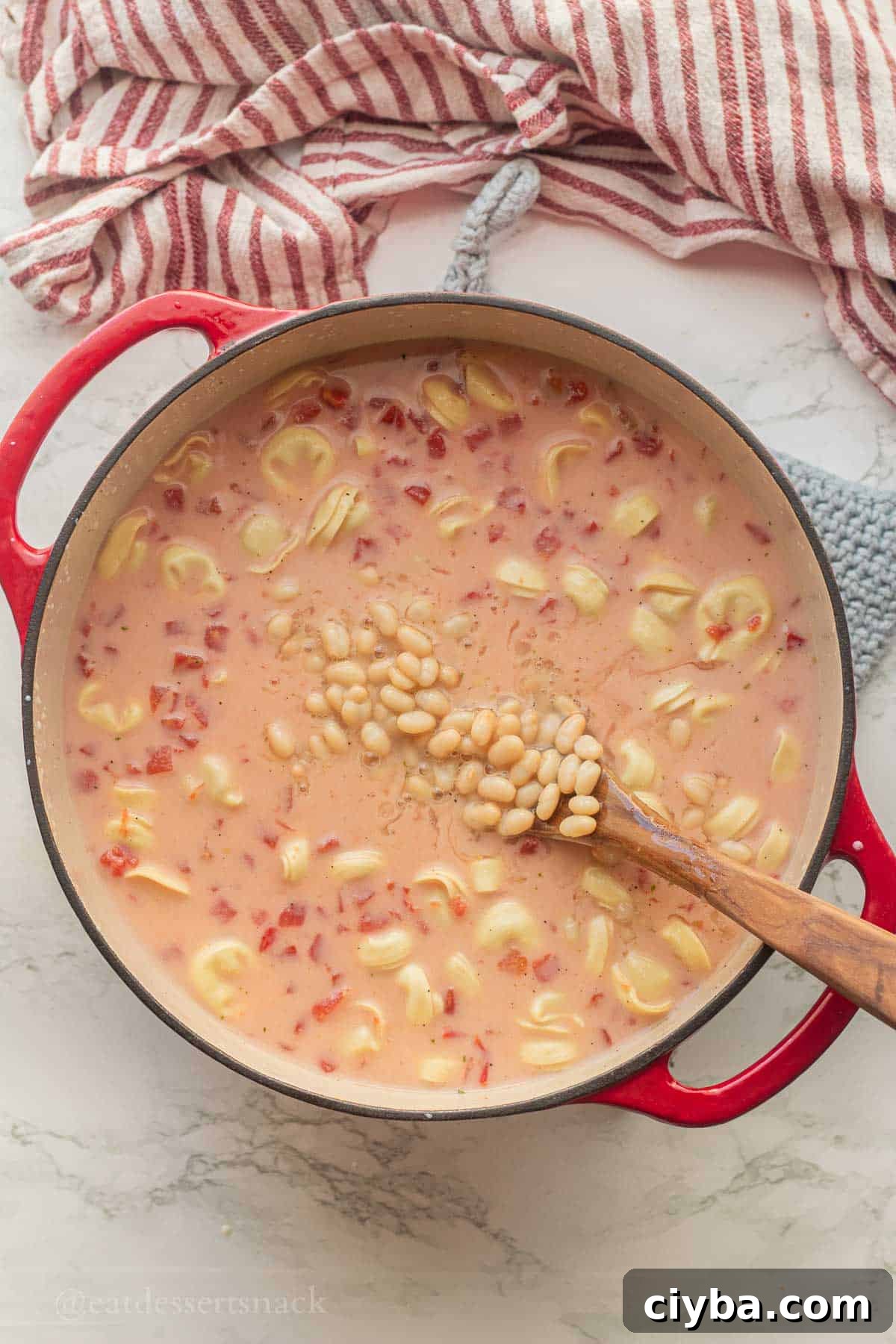 White beans in soup pot with wooden spoon.