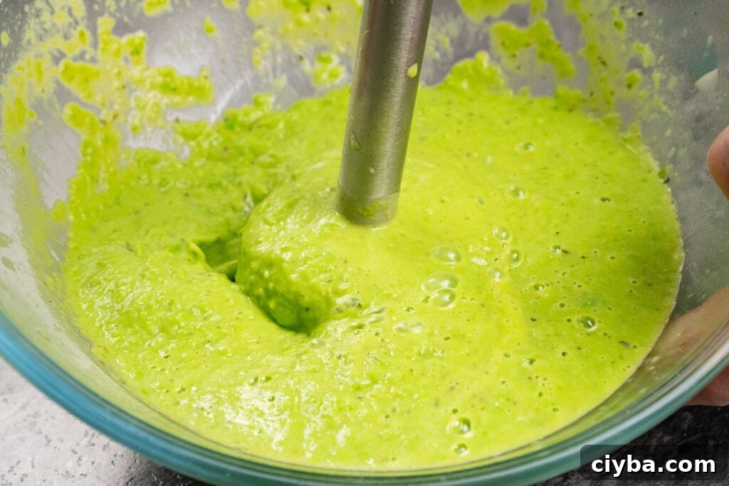 Blending pea puree in a glass bowl with an electric blender