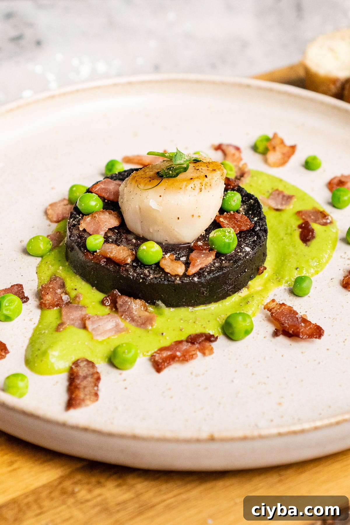 Scallops and Black pudding served on minted pea puree with crispy bacon