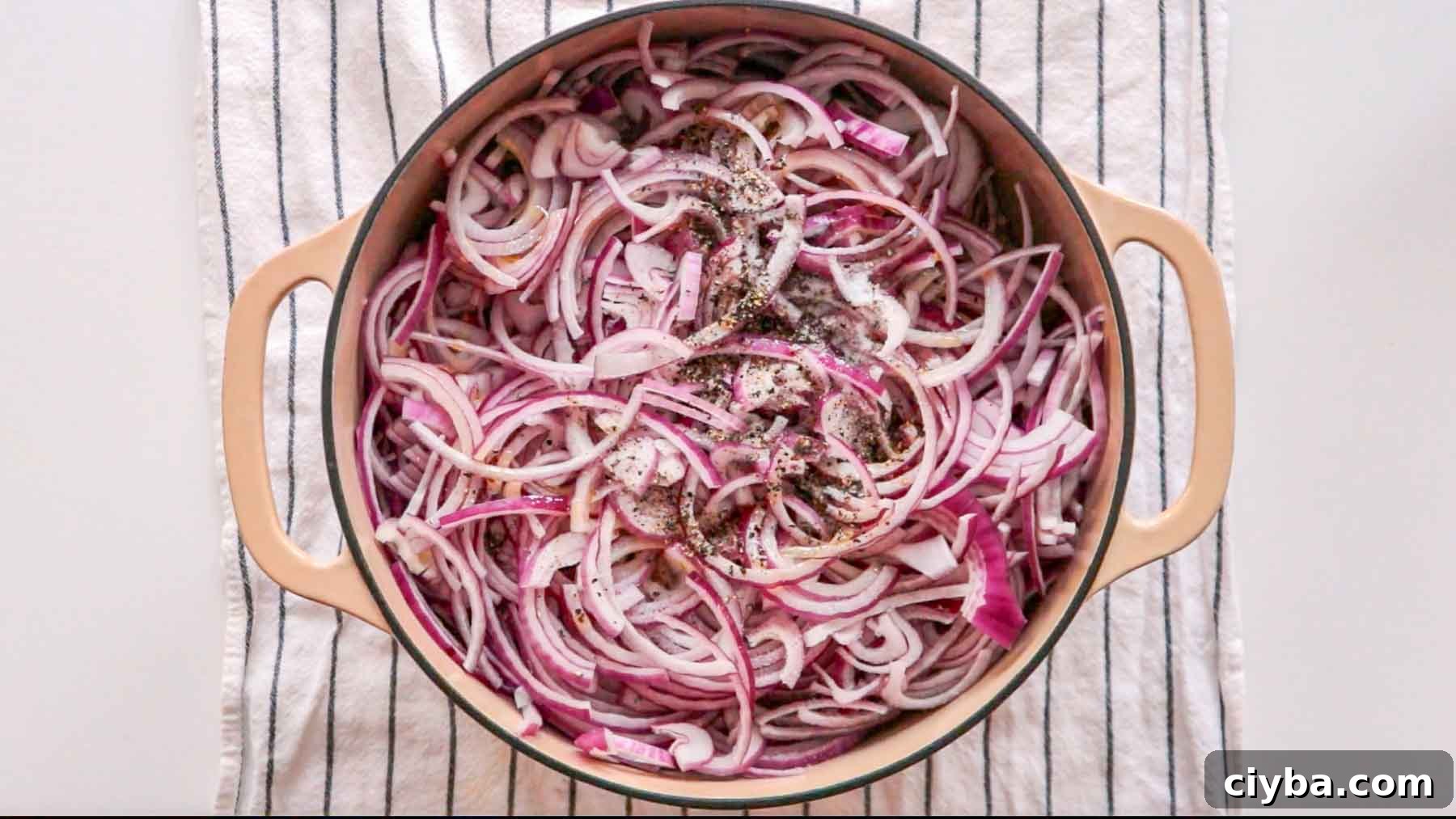 Sliced red onions and black pepper in a dutch oven.