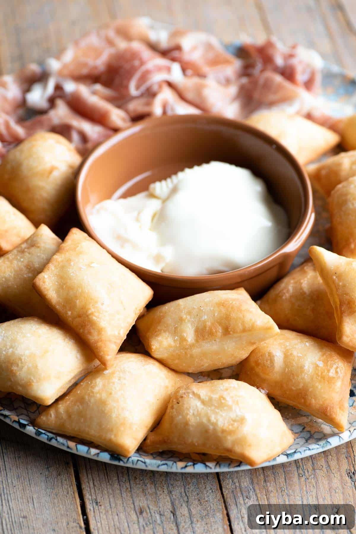 Gnocco Fritto (Italian fried dough) on a plate with cheese and prosciutto.