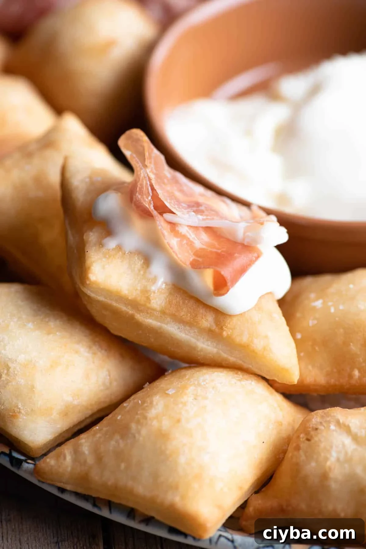 A close up of Gnocco Fritto (Italian fried dough) with cheese and prosciutto on top.