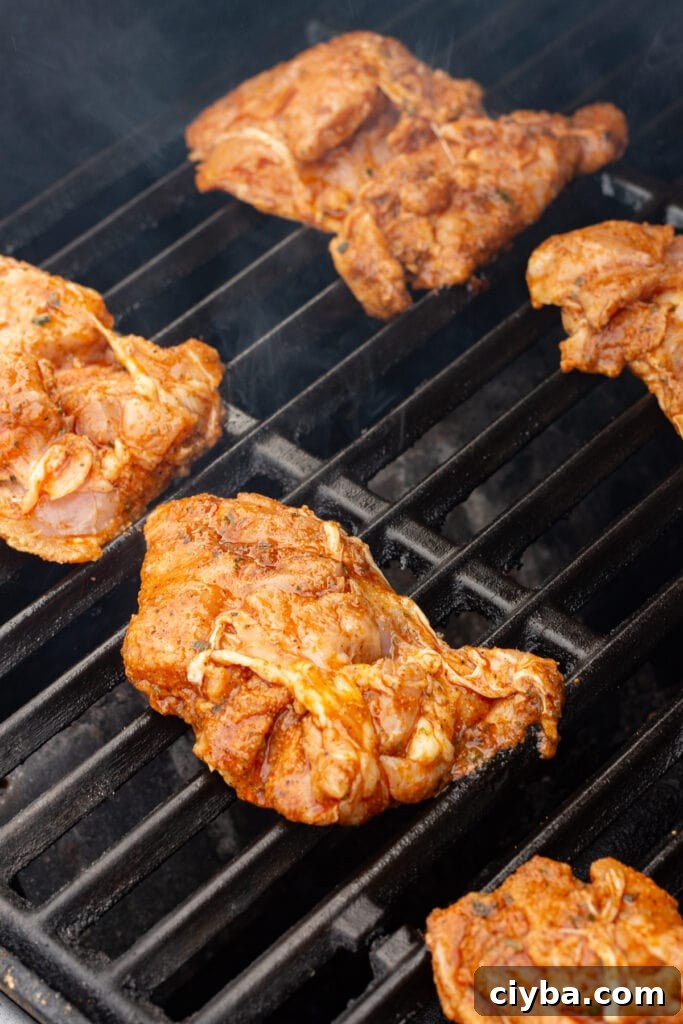 Close up of marinated boneless skinless chicken thighs on a grill.