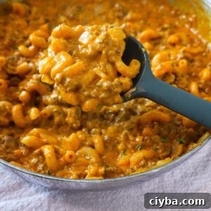 Creamy yellow - orange hamburger helper noodles being scooped with a spoon.