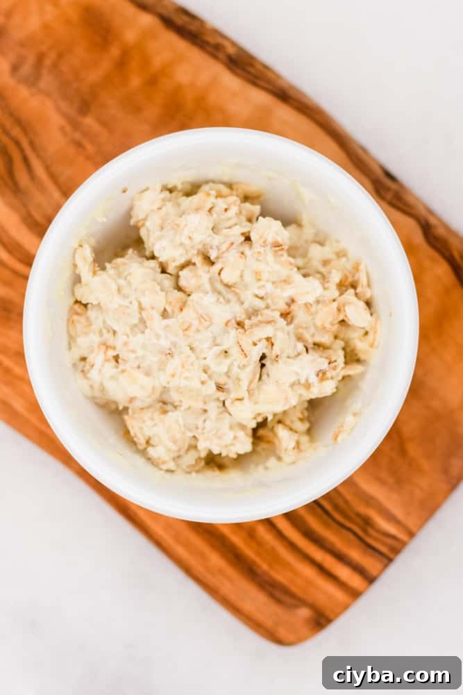 Moisturizing beeswax and oatmeal hand mask on wooden tray.