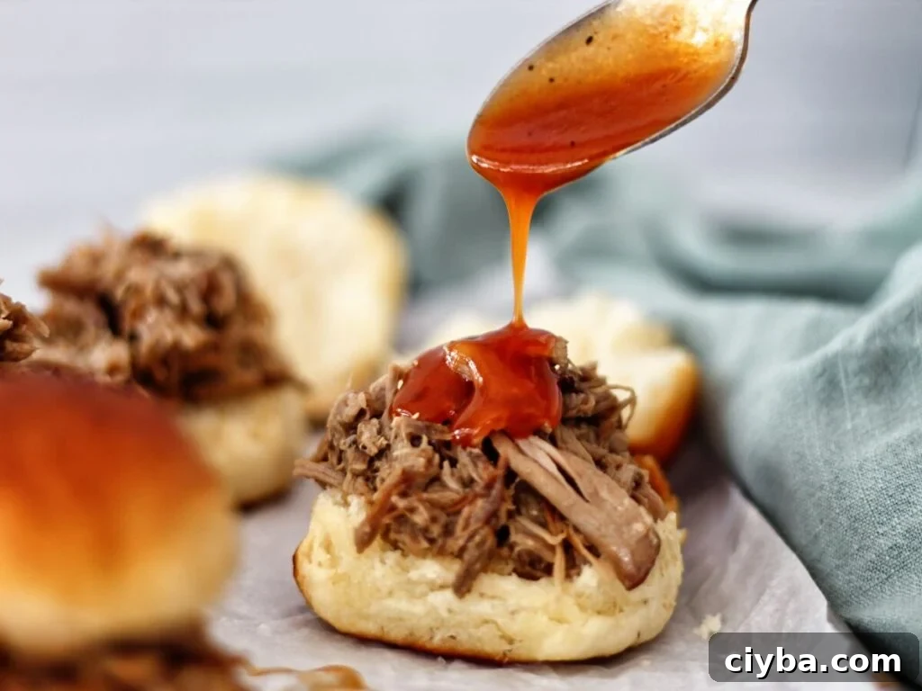 drizzling barbeque sauce onto pulled pork slider.