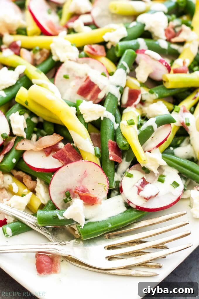 green bean and feta salad with bacon and radishes on a white plate with a fork