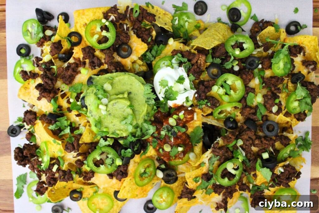 overhead view of air fryer nachos with ground beef, guacamole, and sour cream