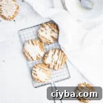 brown butter iced pumpkin cookies on a small silver cooling rack next to a piece of white linen and a bowl.