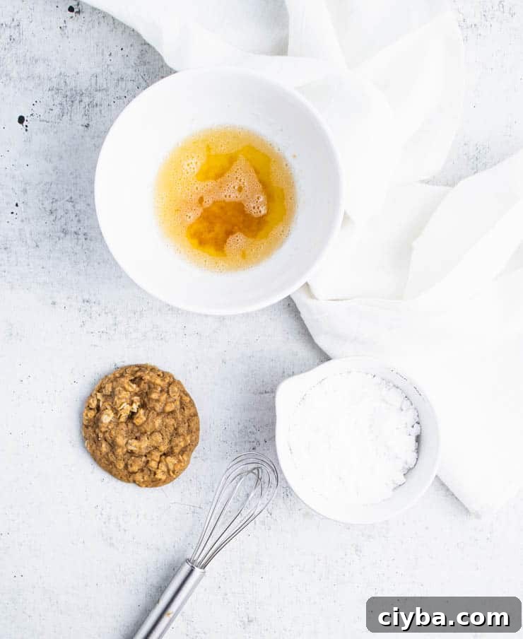 Pumpkin Oatmeal Cookies with Brown Butter Glaze 5 a baked pumpkin oatmeal cookie next to a bowl of browned butter and powdered sugar.