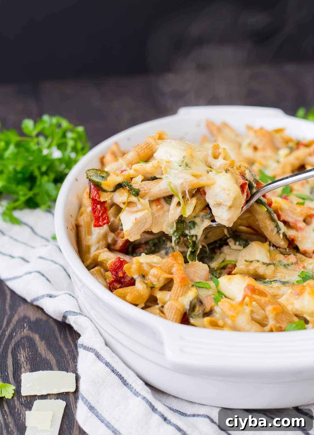 Spoon scooping out a portion of baked pasta from casserole dish.