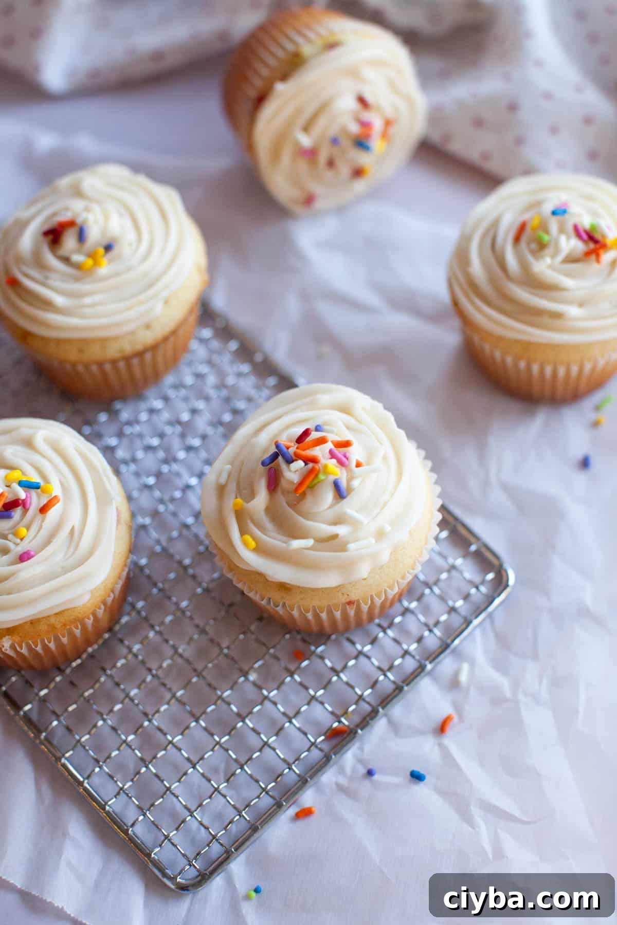 a batch of confetti cupcakes on a cooling rack.