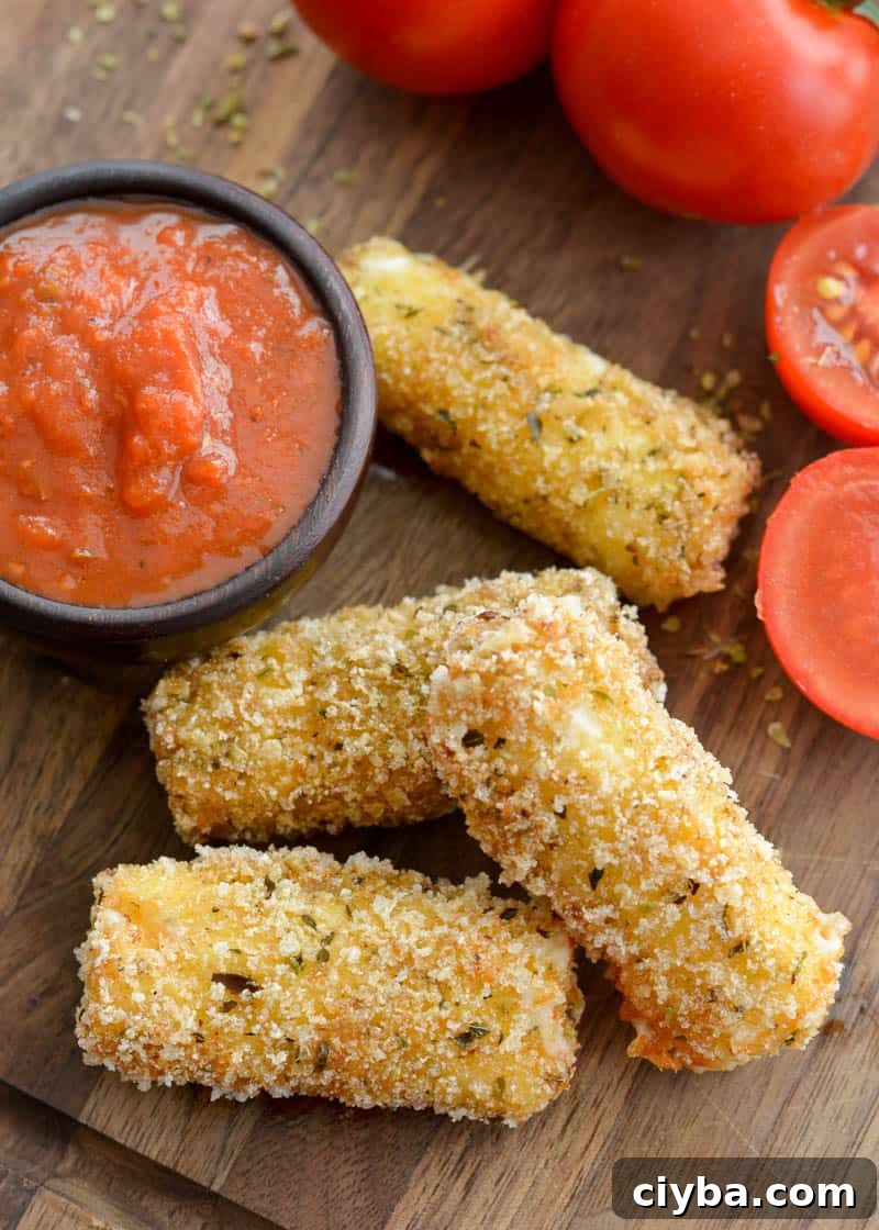 four gluten free mozzarella sticks on a cutting board with marinara sauce