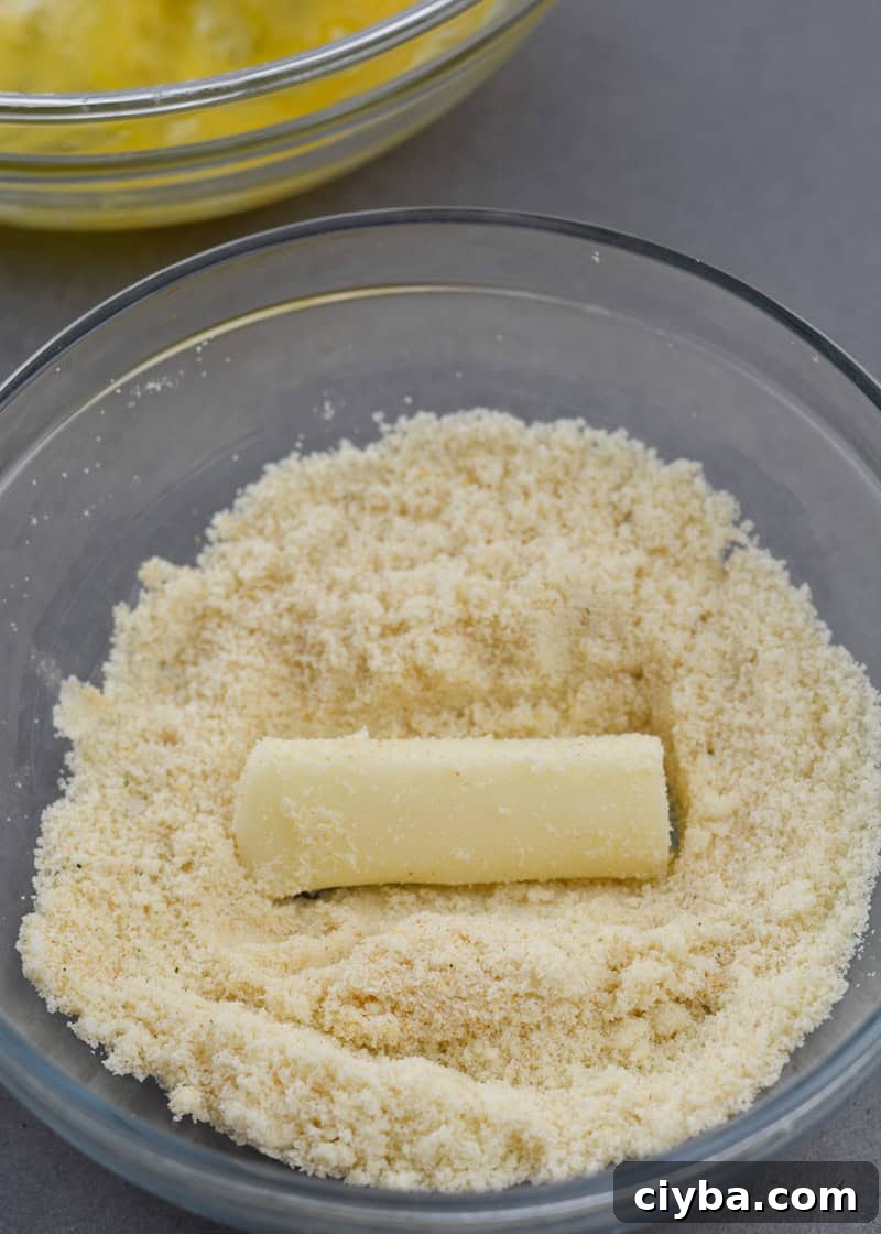cheese stick in a bowl of seasoned almond flour