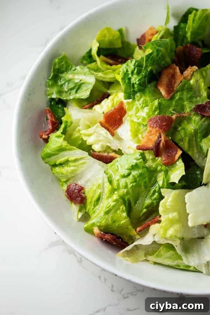 closeup of white bowl containing wilted lettuce salad