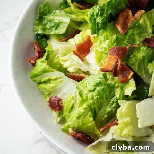 closeup of white bowl containing wilted lettuce salad