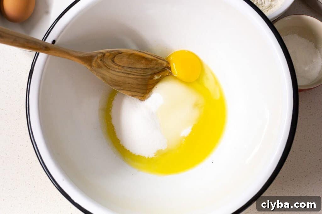 First step of recipe with ingredient in bowl. Egg, sugar and melted butter.