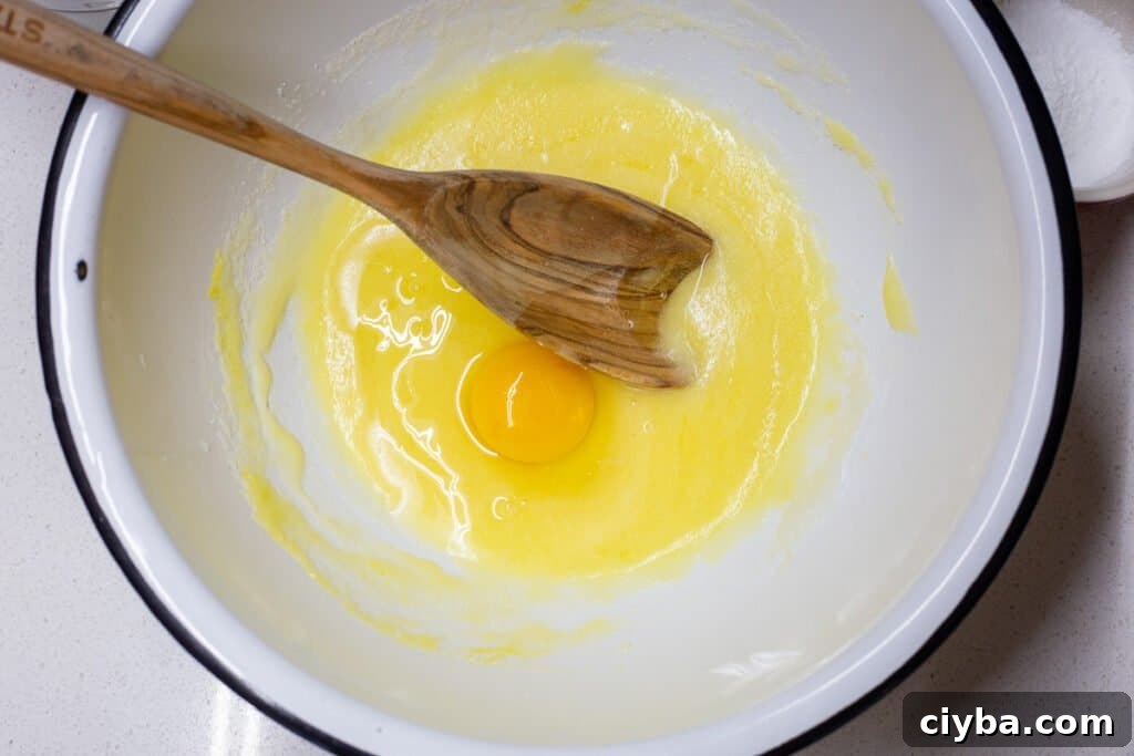Adding another egg to mixture for third step in recipe.
