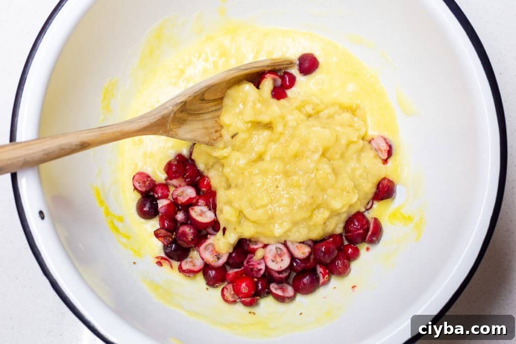 Fourth step in recipe of adding mashed banana and cranberries.