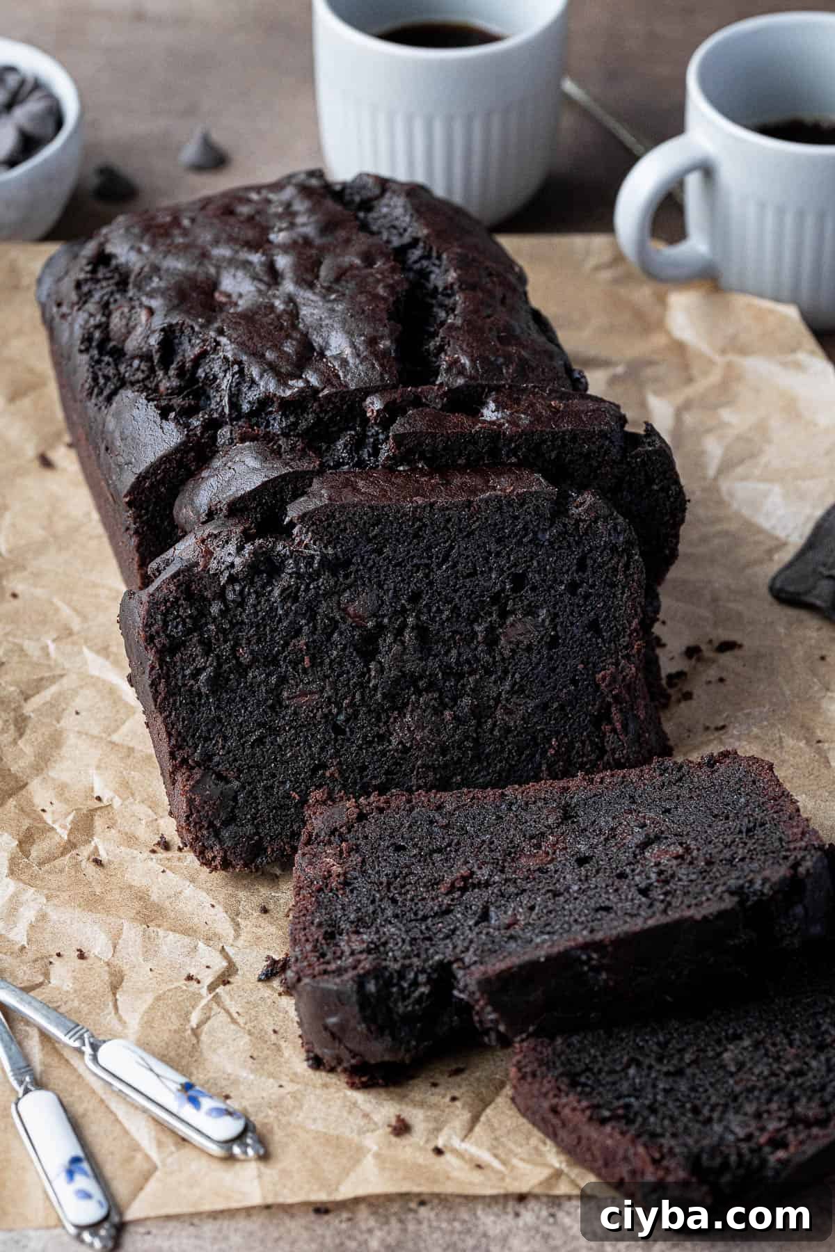 Vegan chocolate courgette cake withh cups of coffee and a bowl of chocolate chips.