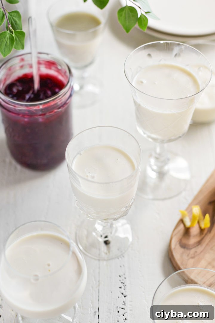 lemon panna cotta in dessert dishes next to a jar of blueberry sauce